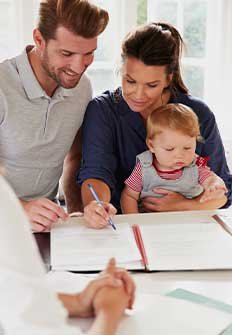 Pareja con un bebe firmando un contrato de seguros.
